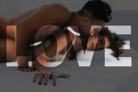 Young Beautiful Couple. Couple is Caucasian Boy and Black Curly Girl. Couple is Lying on Bed. Man Kissing a Girl the Neck. Woman is Feeling a Good. Sexual People is Naked. Sexual Prelude.の写真素材