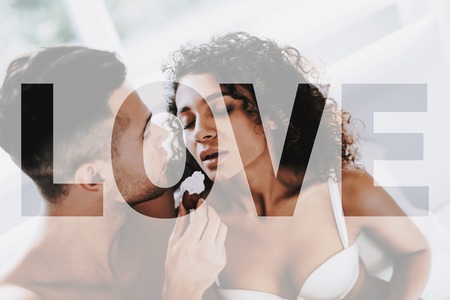 Young Naked Beautiful Couple. Couple is Caucasian Boy and Black Curly Girl. Couple is Sitting on Bed. Man is Feeding a Girl the Strawberry with Whipped Cream. Girl Feeling a Good. Sexual Prelude.の写真素材