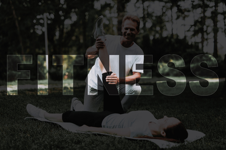 Man Holding Girl's Leg. Woman Lying on Rug for Yoga.の写真素材