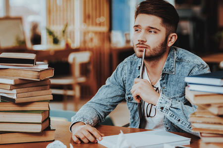 A young man with big pile of booksの写真素材