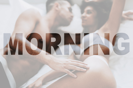 Young Beautiful Couple. Couple is Caucasian Boy and Black Curly Girl. Couple is Lying on Bed. Sexual Persons is Naked. Happy Morning Time. Man Touching a Girl. People Located in Bedroom at Home.の写真素材
