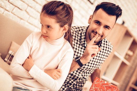 Video Game in Hand. Virtual Reality Mask. Father and Daughter on Sofa. Spend Time Together. Father's day. Man Play with Girl. Video Game. White Interior. Girl in Mask Virtual Reality. Girl Lye on Sofaの写真素材
