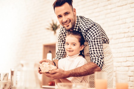 Cook Food at Home. Happy Family. Father's Day. Girl and Man Cooking Smiling Man and Child at Table. Spend Time Together. Food on Table. Egg in Bowl. Pour Flour. Cook Dough. Dough in Hands.の写真素材