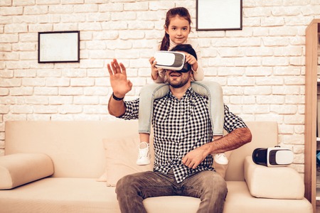 Sit on Sofa. Joystick in Hand. Virtual Reality Mask. Father and Daughter. Spend Time Together....
