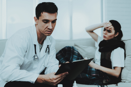 Doctor Visiting Sick Young Woman in Scarf at Home. Sick Young Girl. White Sofa in Room. Doctor in Uniform. Disease Concept. Healthcare and Healthy Lifestyle Concept. Man in White Coat.の写真素材