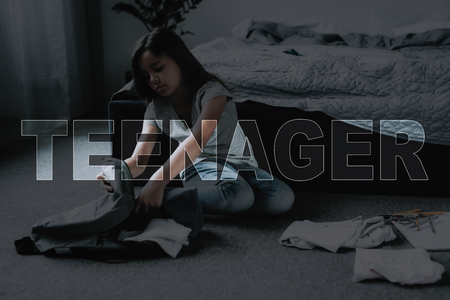 Girl Collects Gray Backpack. Time Go to School. Student Weekdays. Little Black-Haired Girl. Hard Morning. Teenager Back to School. Child Get Up Early. Unhappy Girl. Small Girl Surrounded Stationery.の写真素材