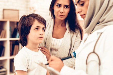 Mother with Son at Arabic Doctor's Appointment. Confident Muslim Female Doctor. Child at the...