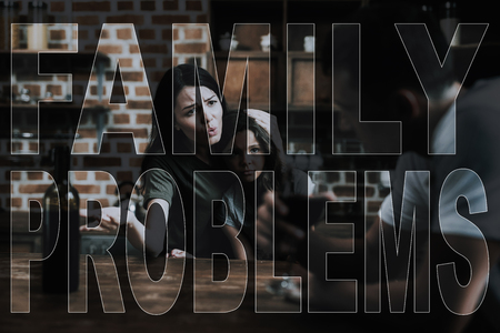 Wife Reproaches Husband. Family Problems. Drunk Man Sit. Man Turned Away with Shame. Mother Hugs Daughter. Man Sit Drinks Wine. Alcoholism Grief for Family. Father Protects Daughter.の写真素材