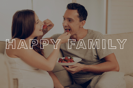Parents Feed Each Other. Happy Young Family. Have Fun. Pregnant Woman Eat Strawberries. Happy Together. Belly Girl Anticipation Pregnancy. Guys Lies on Sofa. Preggers Sit at Home. Smiles Parents.の写真素材
