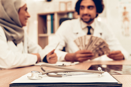 Arabic Doctors Counting Money After Work, Payday. Muslim Doctors Counting Dollars in Office. Arabic Doctors Holding Money, Medical Consultation. Hospital Concept. Healthy Concept. Healthcare And Medicine.の写真素材