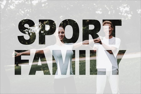 Sport Family in Park. Woman Standing on Yoga Rug. Girl Doing Exercises with Dumbbells. Man Trainer Daughter. Guy Helps Female. Girl in Fitness Training. Person Leads Healthy Lifestyle. Woman Smiles.の写真素材