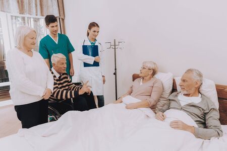 Nurse with Papers. Guests Visit Elderly Couple. Man Dripping. Elderly People Lay in Bed. Nursing Home. Man Sitting in Wheelchair. Smling Group of Patient. Pensioners on Rehabilitation.の写真素材