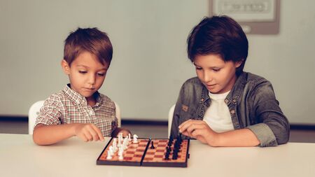 Two Bored Boys Playing Chess Sitting at Table. Thinking Kids.の写真素材