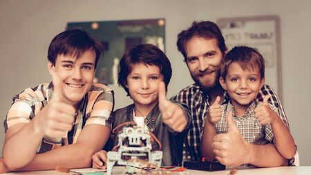 Bearded Father and Sons Constructing Robot at Home. Young Boy in Shirt. Indoor Joy. Modern Hobby Concept. Modern Technology. Robot Engineering Concept. Bearded Young Man. Innovation for Fun.の写真素材