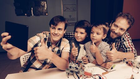 Bearded Father and Sons Constructing Robot at Home. Young Boy in Shirt. Indoor Joy. Modern Hobby Concept. Modern Technology.の写真素材
