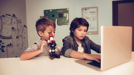 Sitting Boys Using Laptop and Microscope at Home. Young Boys. Microscope on Table. Using Digital Device. Using Keyboard.の写真素材