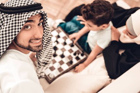 Arabian Boy Playing Chess with Father at Home. Healthy Lifestyle Concept. Smiling Mother. Muslim Family. Smiling Boy at Home. Young Arabian Man. Board Game. Father and Son. Indoor Fun.の写真素材