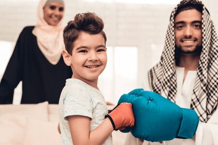Arabian Boy Boxing with Young Father at Home. Healthy Lifestyle Concept. Hand in Gloves. Muslim Family. Smiling Boy at Home. Young Arabian Man. Sports Indoor. Father and Son. Indoor Fun.の写真素材