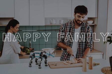 Small Robot in Front. Young Family Cooking. Busy Couple. Happy Family. Girl Smiling. Bubbly Relationships. Young Couple Sit in Kitchen. Guys Have Break. Family Leisure Time.の写真素材
