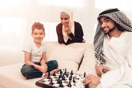 Arabian Boy Playing Chess with Father at Home. Healthy Lifestyle Concept. Smiling Mother. Muslim Family.の写真素材