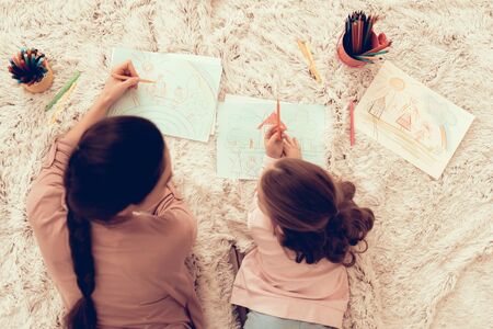 Fun with Daughter. Paper and Pensil. Rest at Home. Child Development. Mom and Daughter Play. Happy Mom and Child in Pajamas. Girl and Mother Lie on Carpet. Colour Pencils. Mom and Daughter Draw.の写真素材