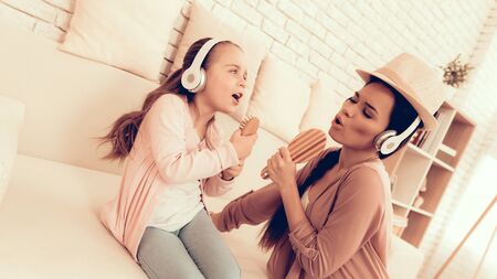 Mother Have Fun with Daughter. Kids Home Games. Learning at Home. Child Development. Mom and Daughter Sing. Girl and Woman in Headphones. Happy Mom and Child in Pajamas. Child with Comb in Hand Sings.の写真素材