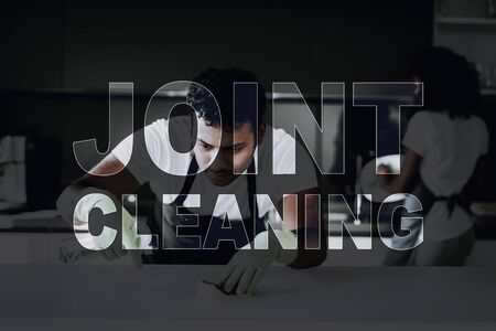 Afro American Couple Kitchen Cleaning Concept. Dish Washing. Table Cleaning. Protective Green Gloves. Household Problem.の写真素材