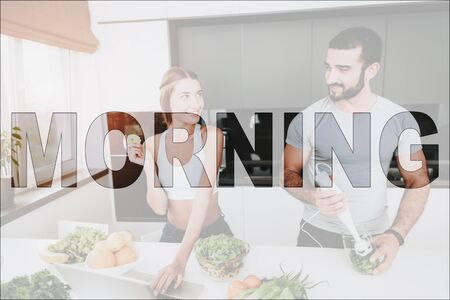 Happy Morning. Athletic Couple in Kitchen. Vegetables and Fruits on Table. Laptop on Table. Couple Prepare a Salad.の写真素材