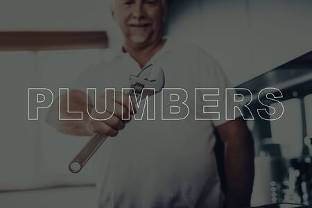 Old Gray Haired Man Posing. Man is Plumber. Plumber Holding a Wrench in Hand. Person is Smiling. Worker Looking into a Camera.の写真素材