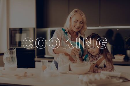 Little Girl Prepare Dough in Glass Bowl. Grandmother Help Girl. Woman in Aprons. Child Make Cookies. Grandmother Smile. Happy Family Cooking. Thanksgiving Day. Girl Cooking Delicious Food.の写真素材