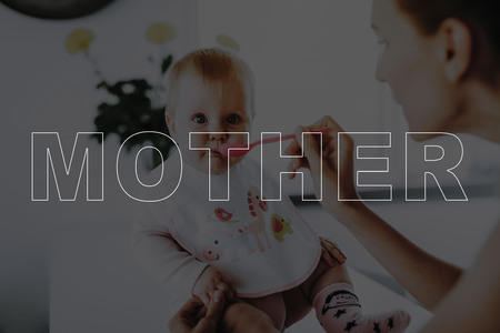 Happy Mom Feeds Adorable Baby. Feeds with Spoon Indoors. Bright Living Room.の写真素材