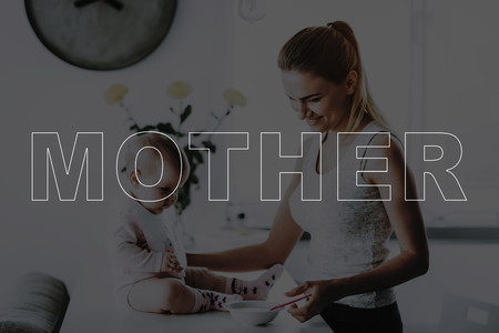Happy Smiling Mother. Mother Feeds Adorable Kid at Home. Bright Living Room.の写真素材
