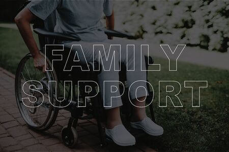 Mature Disabled Woman holding Wheel of Wheelchair. Close up of Sick Mature Woman Sitting in Wheelchair Outdoors. Recovery, Family Support Concept. Patient on Fresh Air Outside Hospitalの写真素材