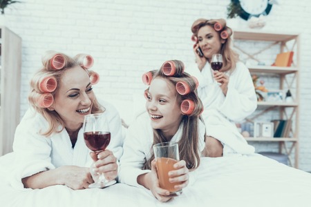 Women in White Bathrobes with Drink in Glasses. Have Fun at Home.の写真素材