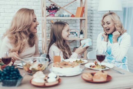 Family Celebrating Grandmother's Birthday at Home. Cake on Table. Happy Family. Mother with Daughter. Smiling Women. Smiling Grandmother.の写真素材