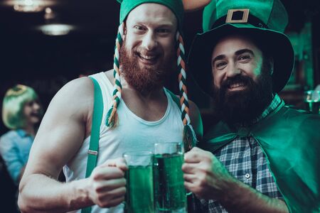 Saint Patrick's Day Party. Group of Friends is Celebrating. People is Drinking a Green Beer. Friends is Young Men and Woman. Happy Men Toast with Each Other. People Wearing a Green Hats. Pub Interior.の写真素材