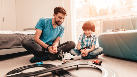 Bearded Father and Son Playing with Toy Race Road. Man Sitting on Floor.