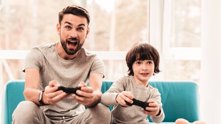 Father and Son Sitting and Playing on Console. Sitting Boy. Young Father. Playing on Console....