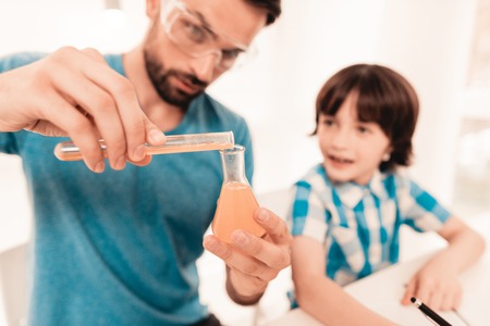 Youn Bearded Father Teaching Son in Shirt at Home. Education at Home. Using Microscope. Studding...