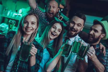 Saint Patrick's Day Party. Group of Friends is Celebrating. Happy People is Toast and Drinking a Green Beer. Friends is Young Men and Women. People Wearing a Green Hats. Pub Interior.の写真素材