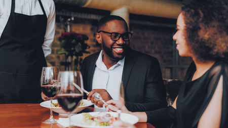 African American Couple Making Order in Restaurant. Romantic Couple in Love Dating. Cheerful Man and Woman with Menu in a Restaurant Making Order. Romantic Concept. Anniversary. Date. Love. Waiter.の写真素材