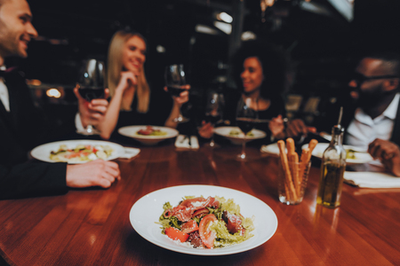 Group of Happy Friends Meeting and Having Dinner. Celebrating with Friends. Party Dinner Table. Enjoying Meal In Restaurant. Restaurant Chilling Out Classy Lifestyle Reserved Concept.の写真素材