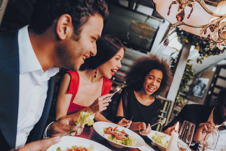 Group of Happy Friends Meeting and Having Dinner. Celebrating with Friends. Party Dinner Table. Enjoying Meal In Restaurant. Restaurant Chilling Out Classy Lifestyle Reserved Concept.の写真素材