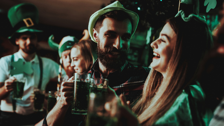 Young Company Are Celebrating St Patrick's Day. Bar Counter. Alcohol Handling. Black Beard. Smiling Teenagers. Carnival Clothes. Bright Lights. Club Visitors. Funny Hats. Beer Drinking.の写真素材