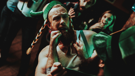 Two Men Fight In Pub. Saint Patrick's Day Concept. Punch In The Face. Quarrel In The Bar. White Singlet. Agressive Males. Angry Guys. Violence In The Club. Funny Hats. Bright Lights.の写真素材