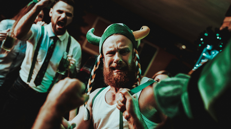 Two Men Fight In Pub. Saint Patrick's Day Concept. Punch In The Face. Quarrel In The Bar. White Singlet. Agressive Males. Angry Guys. Violence In The Club. Funny Hats. Bright Lights.の写真素材