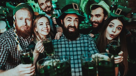 Black Bearded Man With Company. St Patrick's Day. Bar Counter. Alcohol Handling. Smiling Teenagers. Good Festive Mood. Bright Lights. Funny Club Visitors. Celebrating Together. Night Party.の写真素材