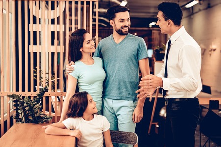 Young Family Consulting With Furniture Seller. Happy Together. Bright Office. Sunny Day. Presentation On A Laptop. Business Meeting. Room Interior. Parents And Daughter. Look Around The Store.の写真素材