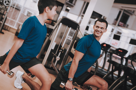 Young Father and Son Doing Exercises in Sport Club. Healthy Lifestyle Concept. Sport and Training Concepts. Modern Sport Club. Sport Equipment.の写真素材