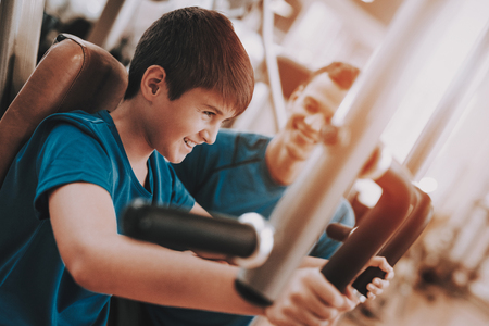 Young Father and Son Doing Exercises in Sport Club.